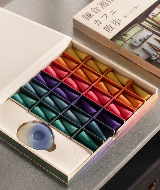 Colorful incense cones in a box with smoke rising on a wooden surface