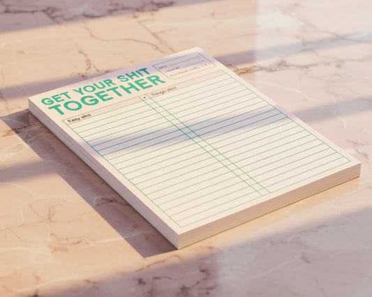 Notepad with text 'Get your shit together' on a pink background