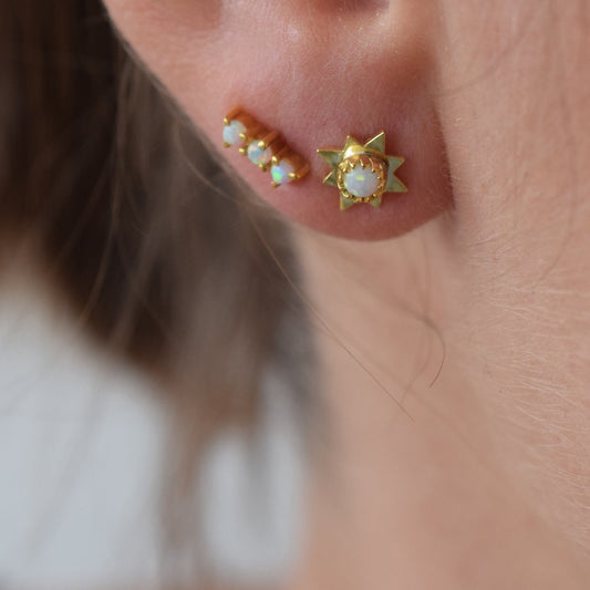 A pair of gold-colored opal starburst stud earrings with simulated opal cabochons.