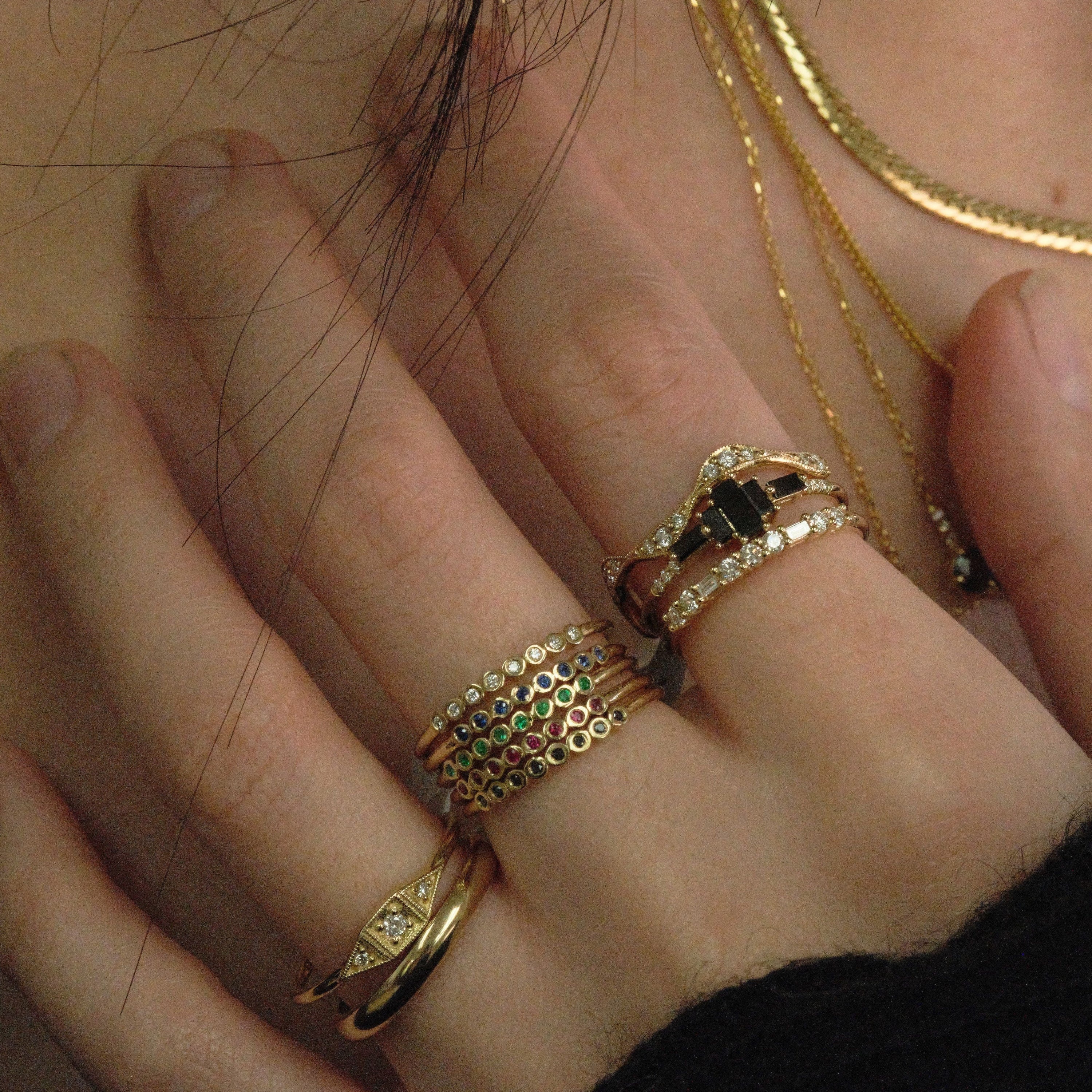 Jennie Kwon rings stacked on model's hand. Including black diamonds, rubies, emeralds and white baguette diamonds