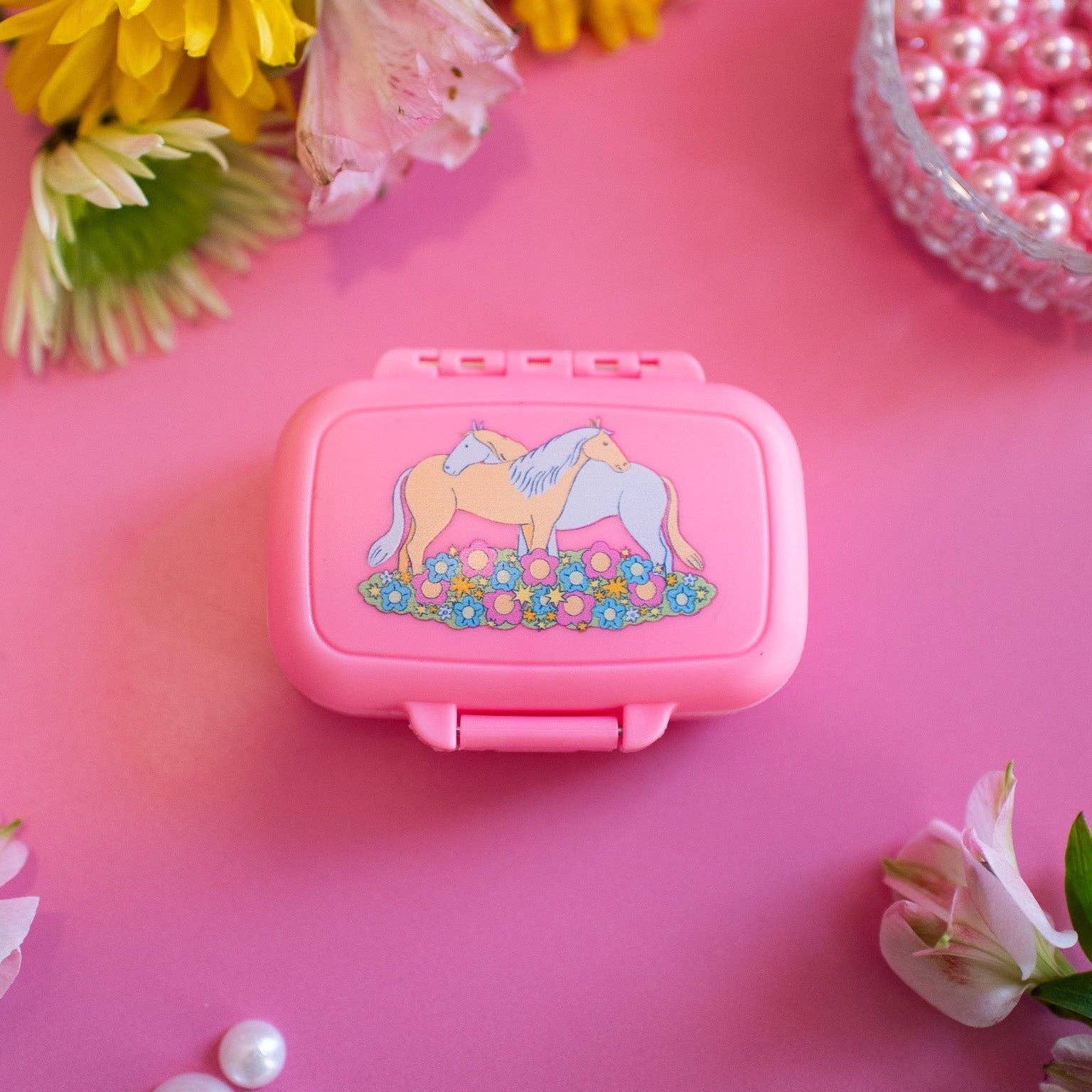 Pink container with a horse design on a pink background with flowers and pearls