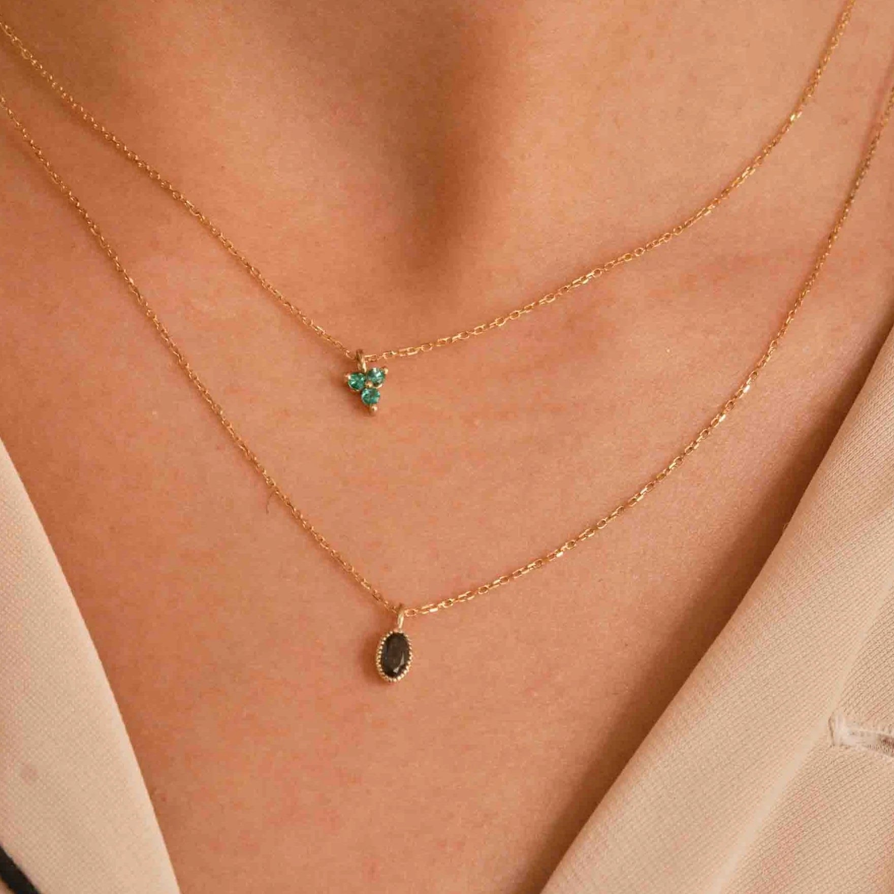 Jennie Kwon black diamond necklaces paired with a small emerald necklace.