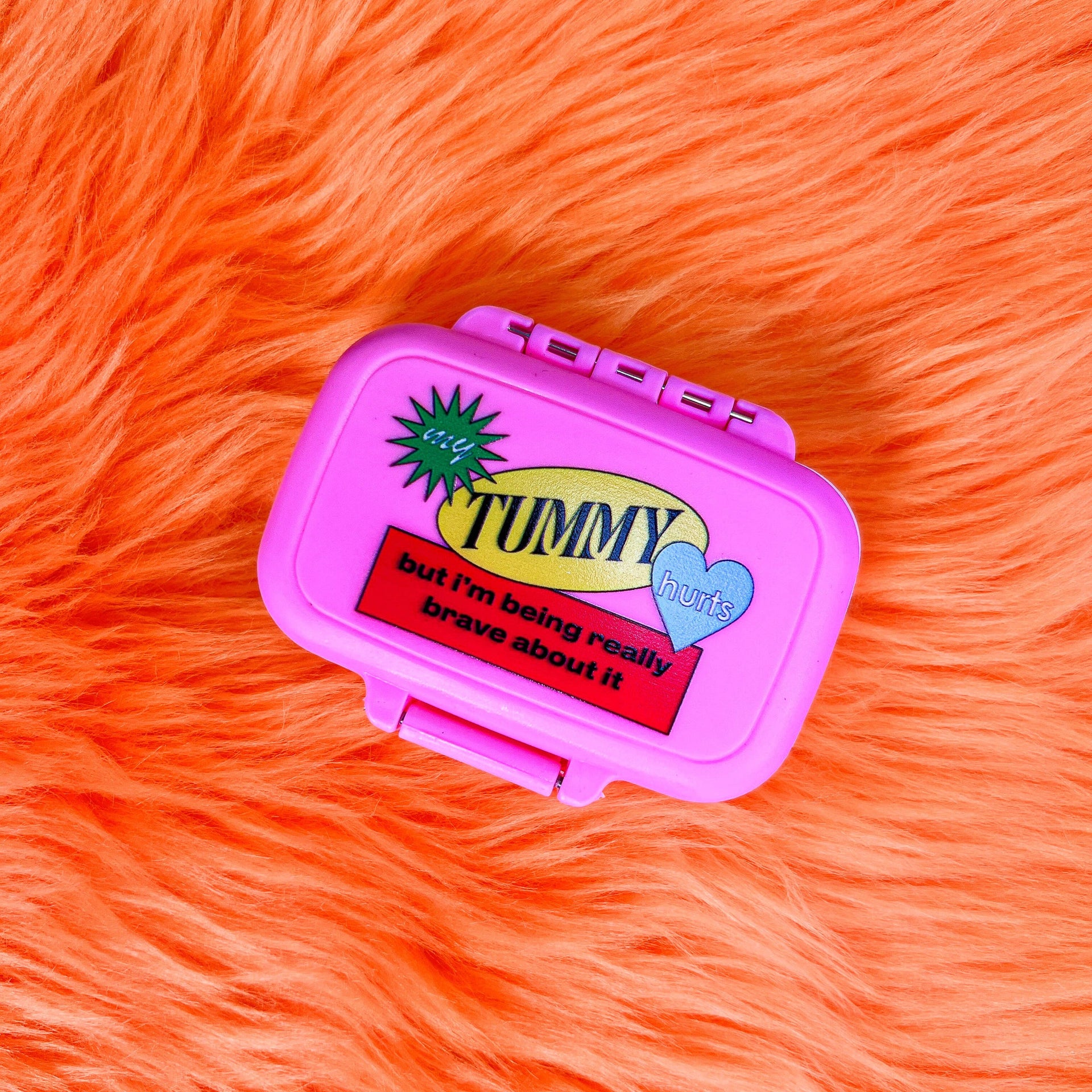 Pink pill box with text on an orange fur background