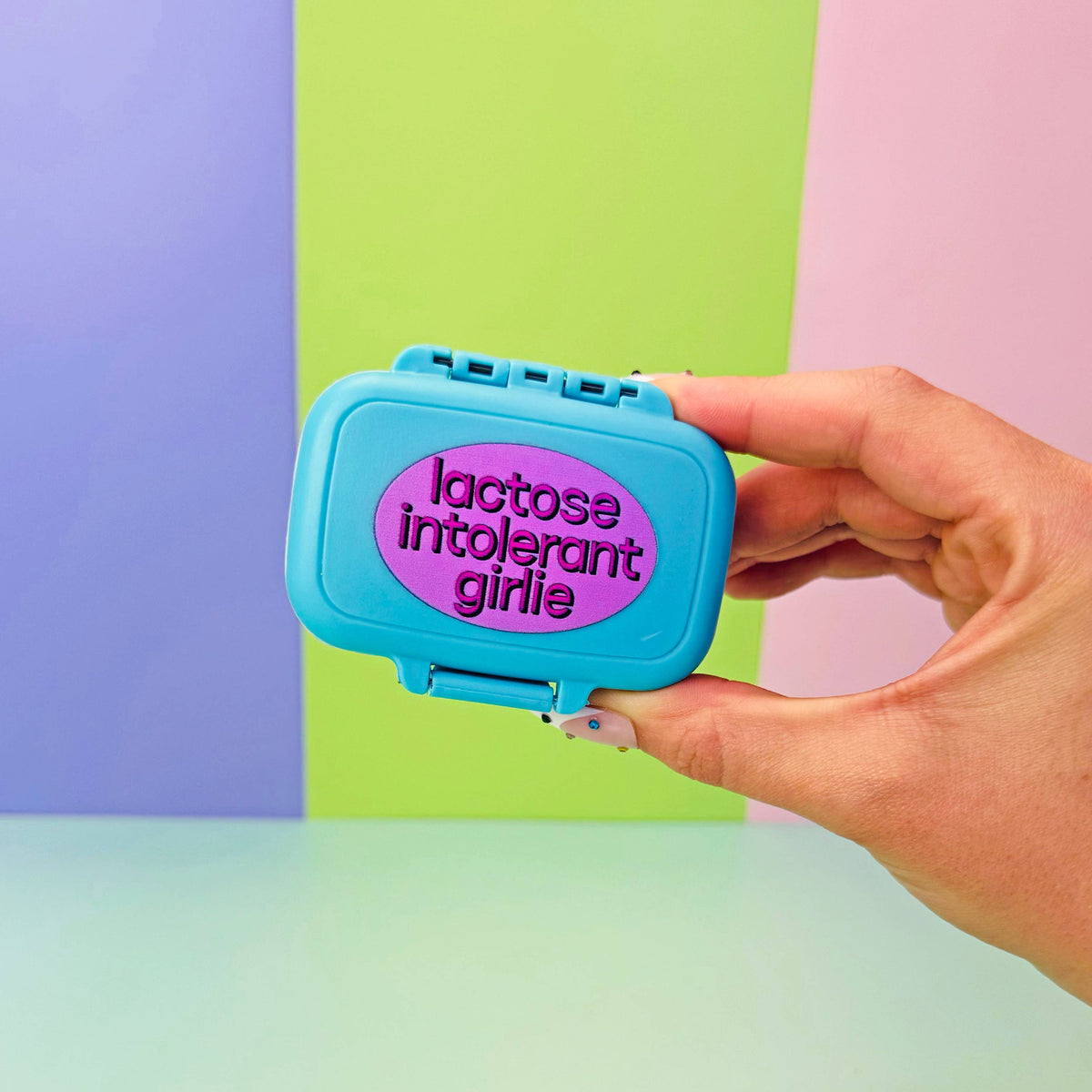 Hand holding a blue container with 'lactose intolerant girl' text against a colorful background