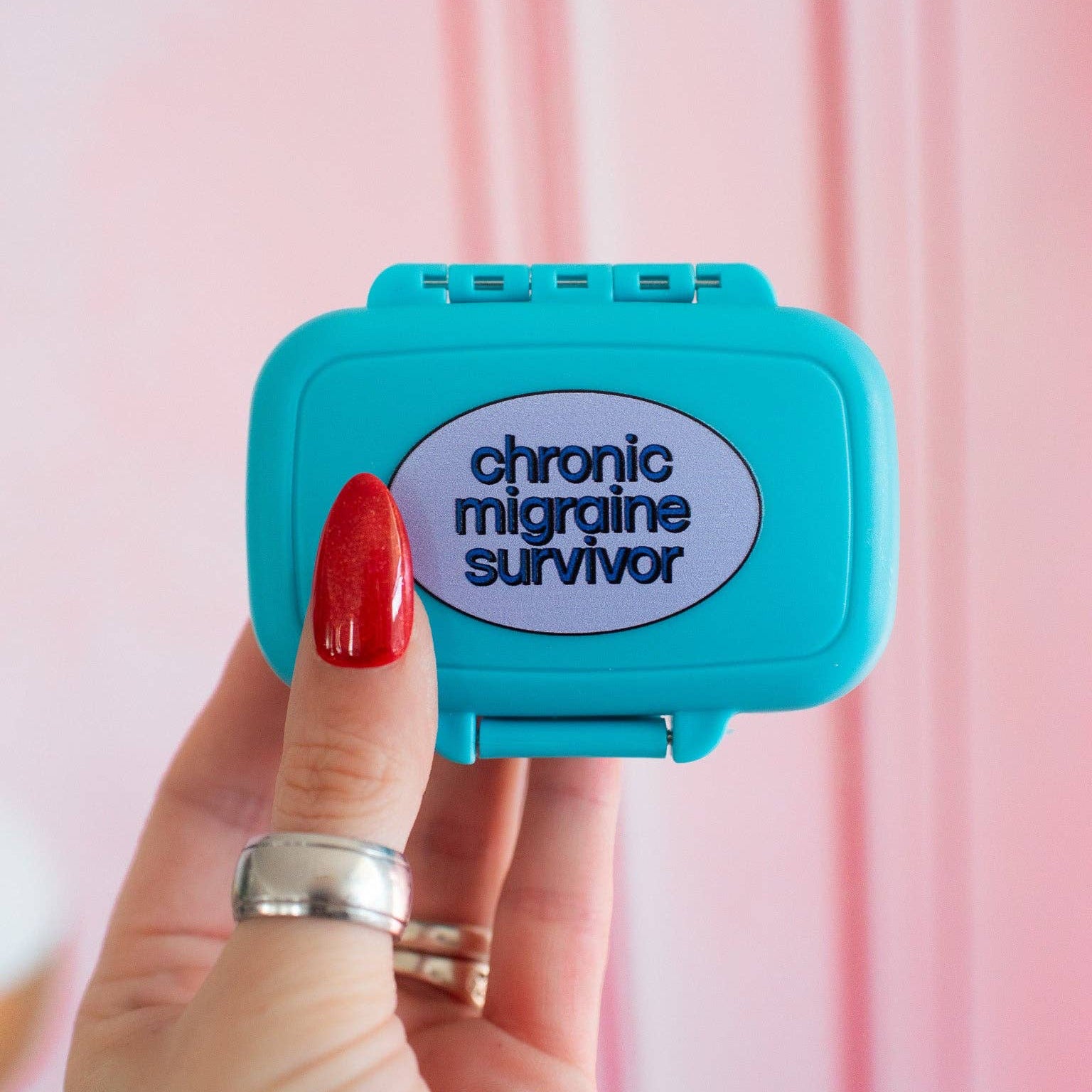 Blue case with 'chronic migraine survivor' text held by a hand against a pink background