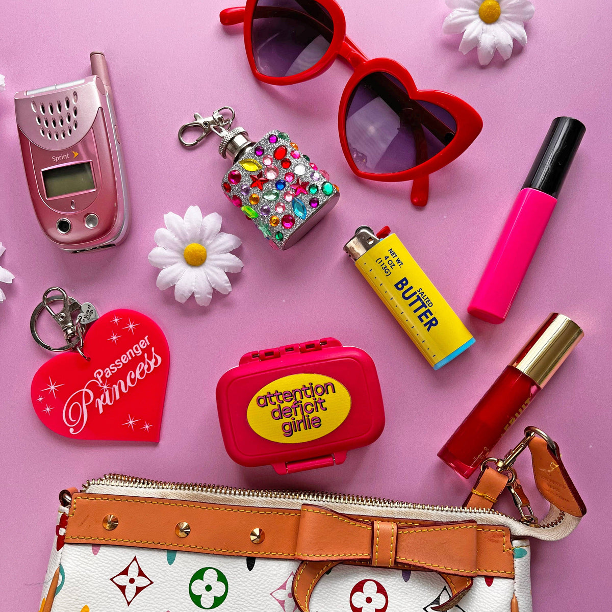 Collection of colorful items including a handbag, lip products, and accessories on a pink background