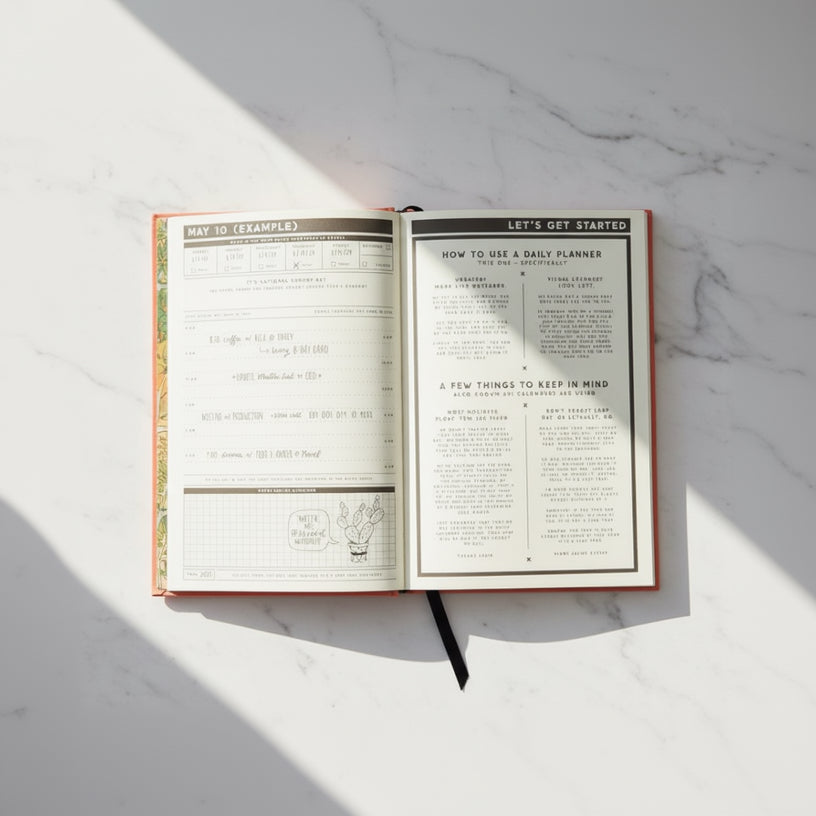 Open daily planner book with instructions on a white marble background