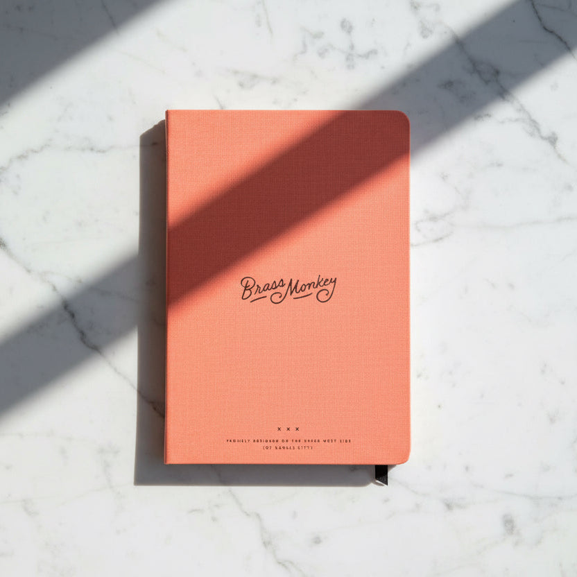 Coral notebook with 'Brass Monkey' branding on a white background