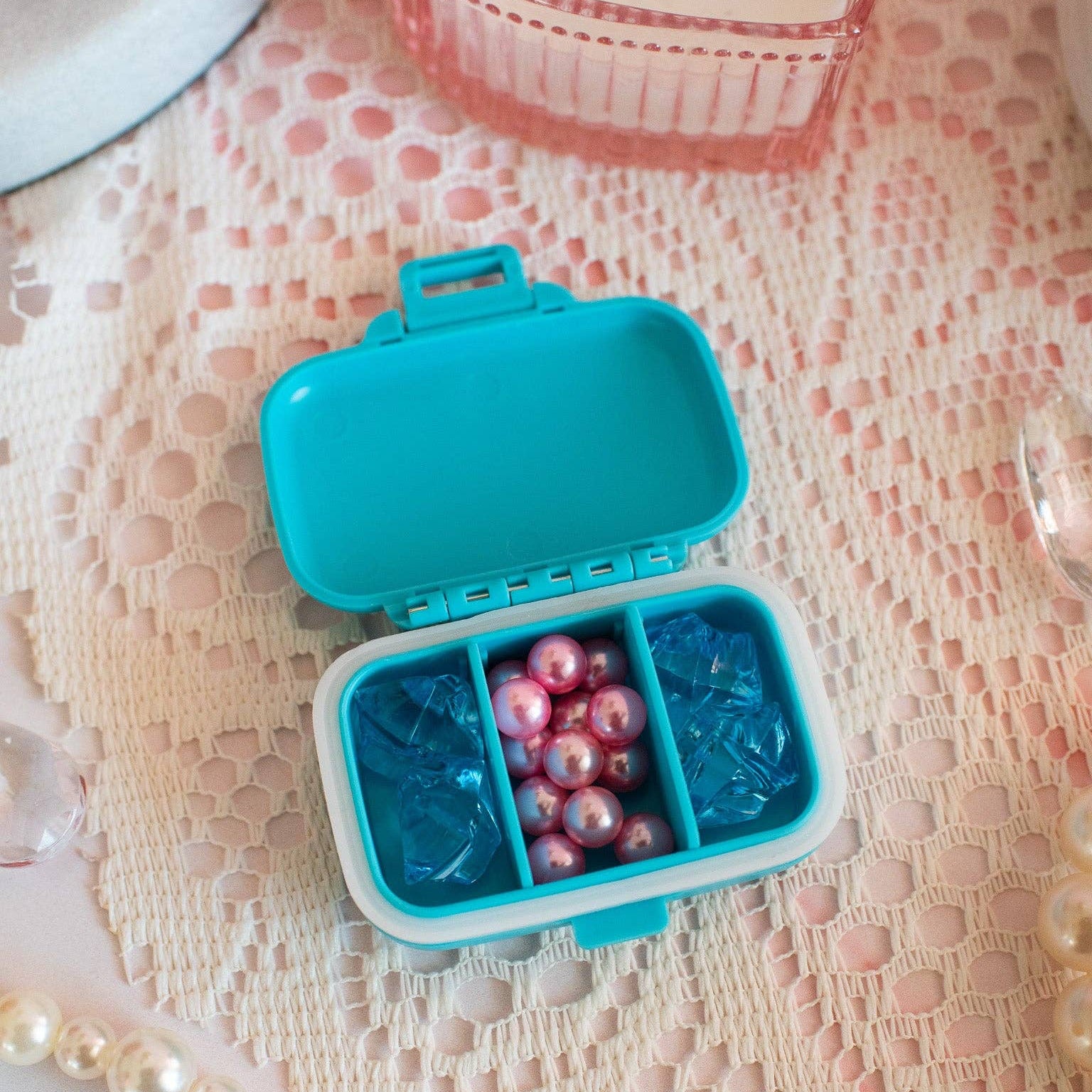 Blue pill organizer with pearls and blue gems on a lace surface