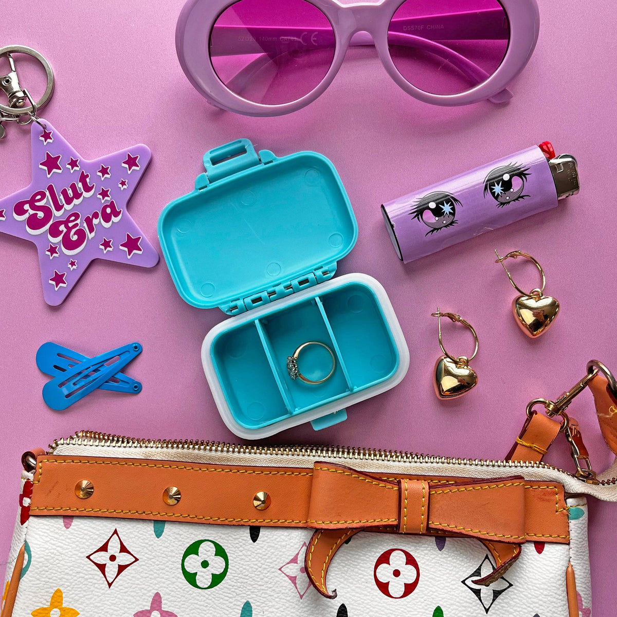 Collection of accessories including sunglasses, lip balm, and handbag on a pink background
