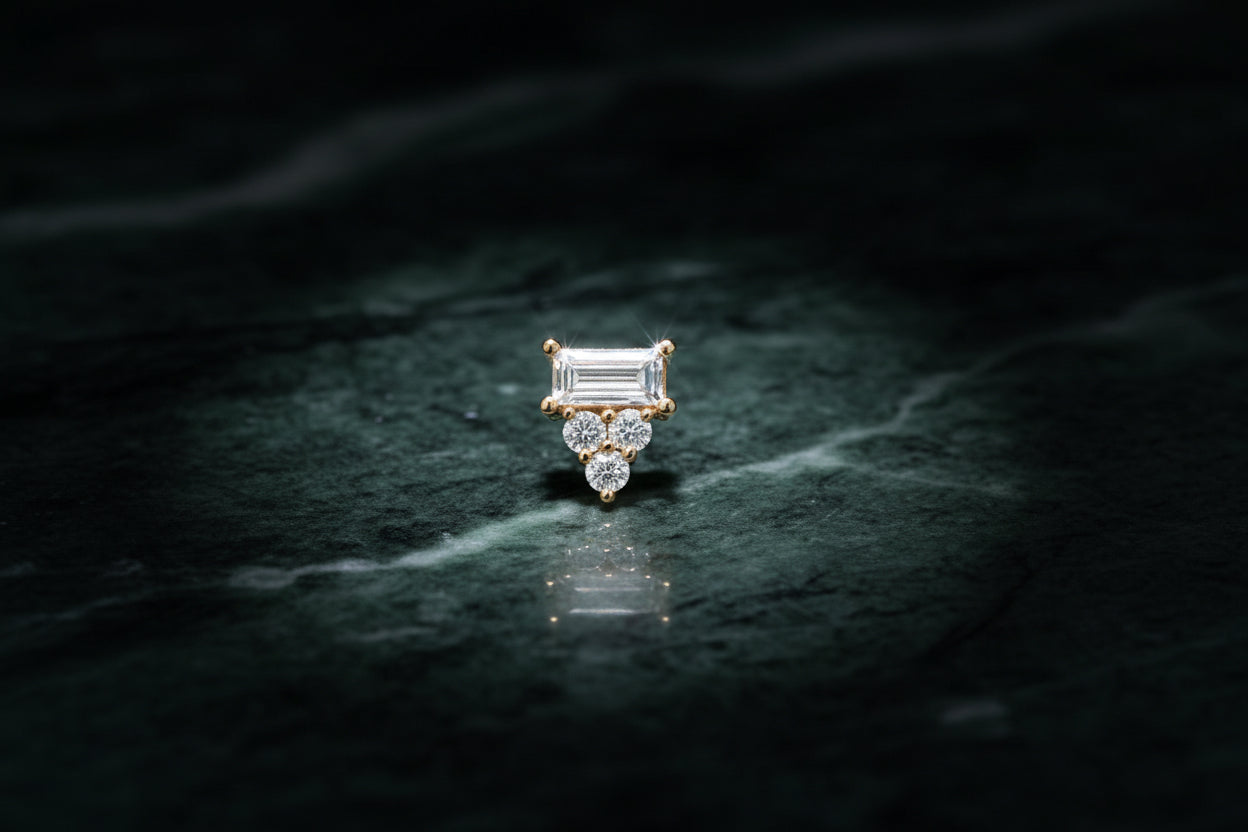 Gold earring with a central diamond and smaller diamonds on a dark background