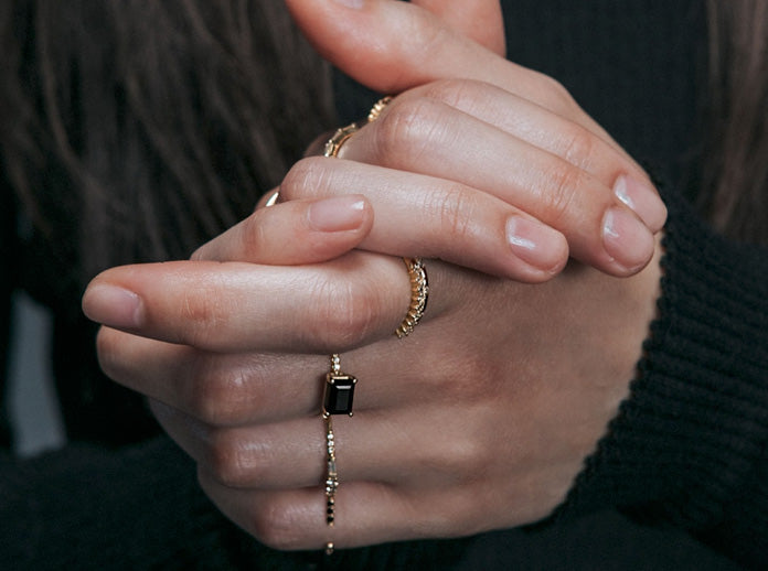 Jennie Kwon black diamond rings on a model with h ands clasped together