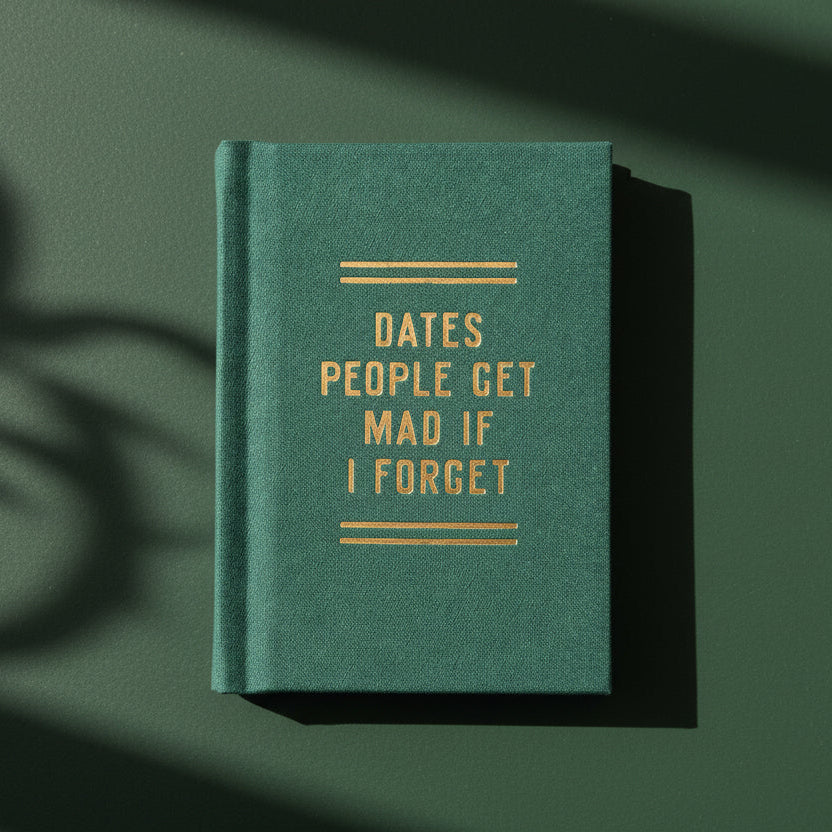 Green notebook with gold text on a white marble background