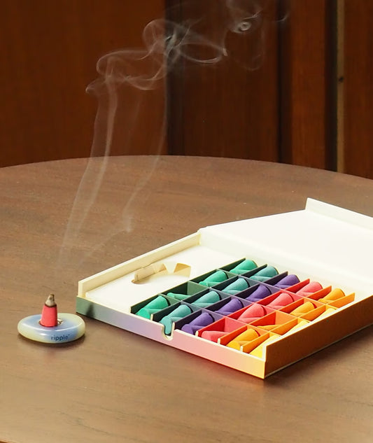 Colorful incense cones in a box with smoke rising on a wooden surface
