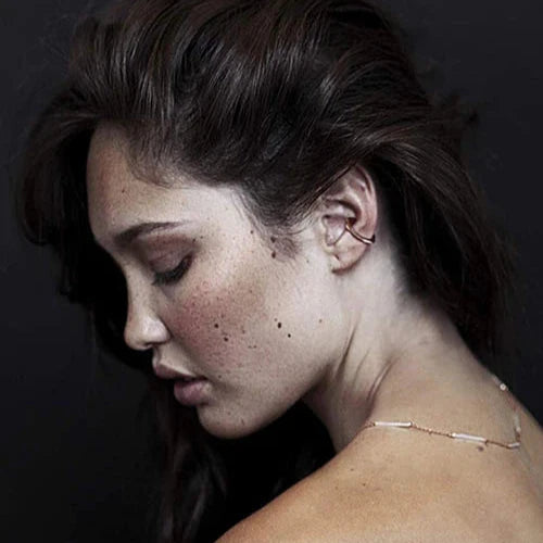 Woman with dark hair and minimal makeup against a dark background wearing Tada and Toy Sky Atlas rose gold and silver necklace