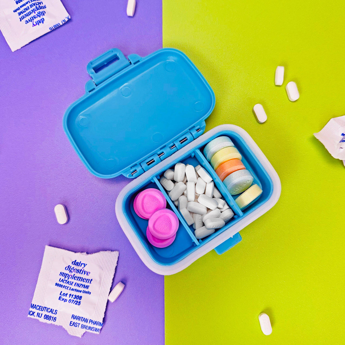 Blue pill organizer with compartments on a purple and green background