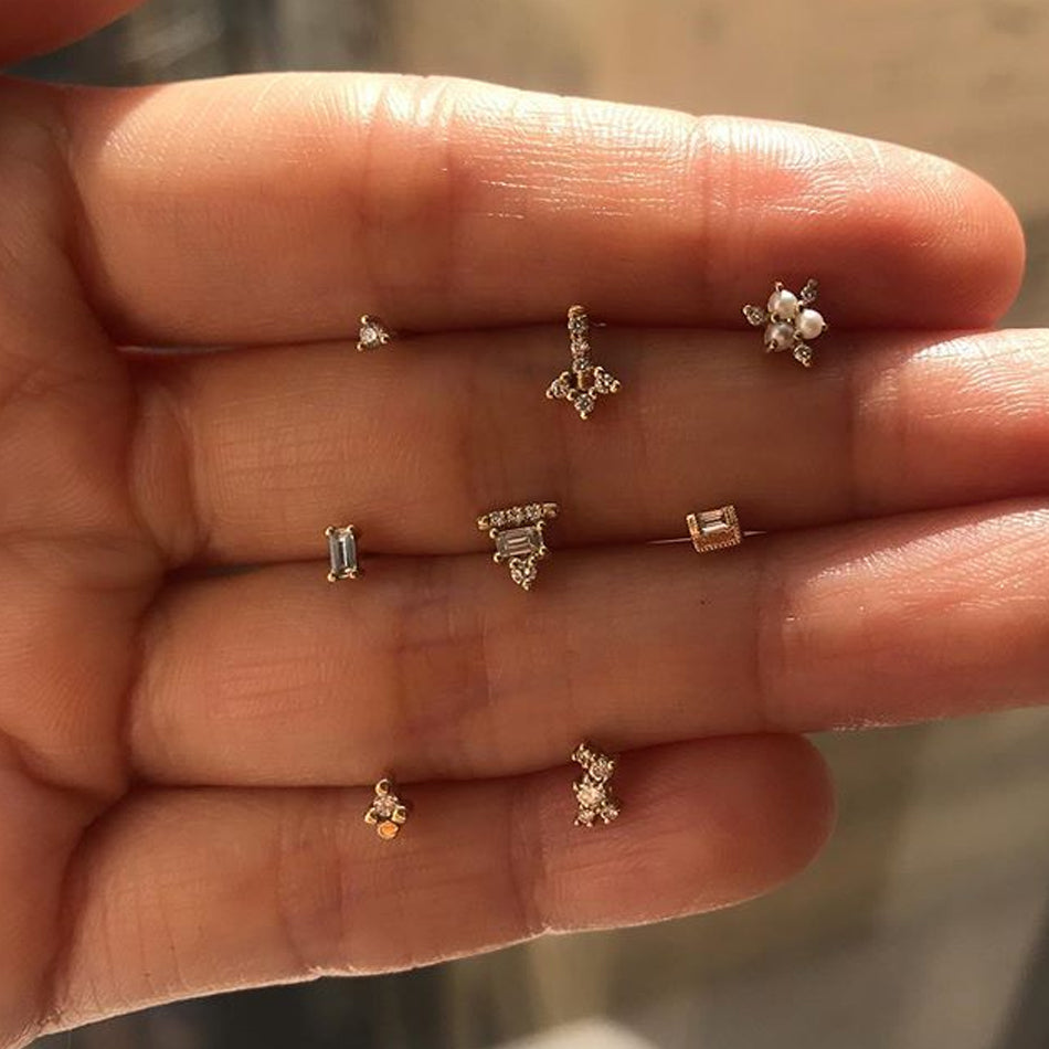 Mix of Jennie Kwon earrings positioned on model's hand